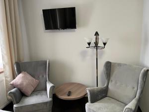 een woonkamer met 2 stoelen, een tafel en een tv bij Spalskie Pokoje Gościnne in Spała