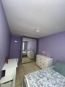 um quarto com paredes roxas, uma cama e um espelho em La Violette ONLY WOMEN femmes uniquement em Vénissieux