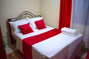 1 Schlafzimmer mit 2 Betten mit roten und weißen Kissen in der Unterkunft Casabella Apartment - Pristine Homes,Tom Mboya in Kisumu