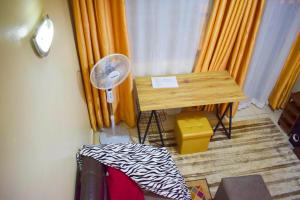 Casabella Apartment - Pristine Homes,Tom Mboya في كيزيمو: غرفة بها مكتب ومروحة وستائر