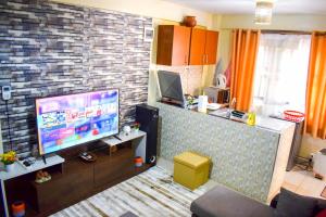 a living room with a tv and a brick wall at Casabella Apartment - Pristine Homes,Tom Mboya in Kisumu