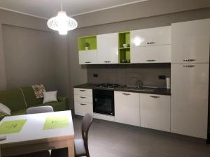 a kitchen with white cabinets and a table and a sink at Corallo Neroo in Milazzo