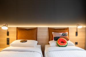 a room with two beds with a watermelon on the pillow at Moxy Dresden Neustadt in Dresden