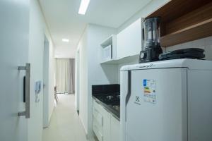 a white kitchen with a refrigerator and a stove at Porto Star Prime By AFT in Porto De Galinhas