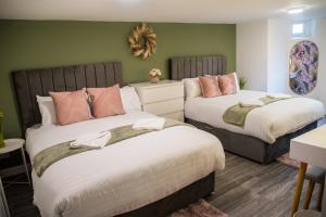 two beds in a room with green walls at Blackpool Abode - Beach Garden Apartment in Blackpool