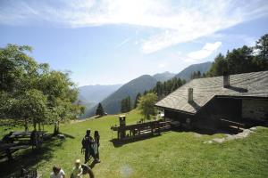 a group of people standing in a field near a barn at Baita Vioz in Peio +17 photos