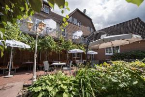 un patio con mesas y sombrillas frente a un edificio en Landhotel für Familien und Firmen en Schönhagen