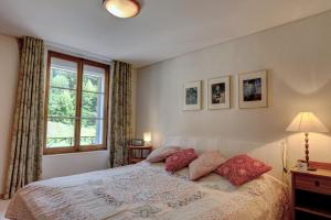 a bedroom with a bed with red pillows and a window at Appartement Rosat 6 in Chateau-d'Oex +13 photos