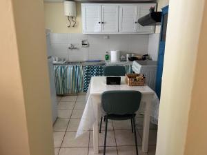 una pequeña cocina con mesa y sillas verdes en Yiayia Katina’s House en Korinthos