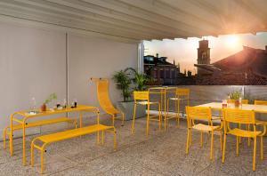 ein Restaurant mit gelben Tischen, Stühlen und einem Tisch in der Unterkunft BnBiz - Coworking Hotel in Fiorenzuola dʼArda