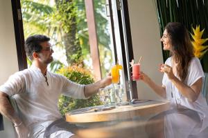 un hombre y una mujer sentados en una mesa con bebidas en Luxe Villas Bali, en Ubud
