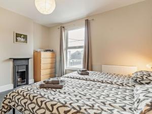 two beds in a room with a fireplace and a window at Harbour Walk in Brightlingsea