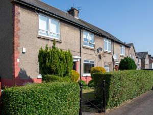 a brick house with bushes in front of it at Pass the Keys Private Entrance GF 2 bed flat near Renfrew Centre in Renfrew