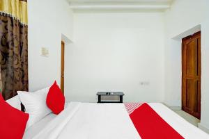 um quarto com uma cama branca e almofadas vermelhas em OYO K B Residency em Chennai