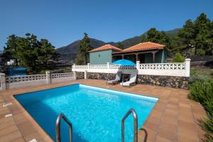 Casa piscina y naturaleza en La Palma في إل باسو: شخص جالس تحت مظله بجانب مسبح