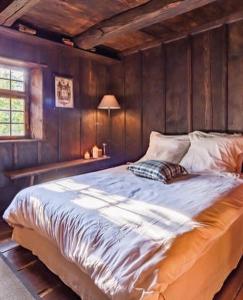 ein großes Bett in einem Schlafzimmer mit Holzwänden in der Unterkunft La Ferme de Marie in Rangen