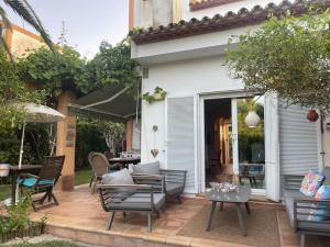 een patio met stoelen, een tafel en een parasol bij Maison cosy au pied du golf in Muntanya la Sella