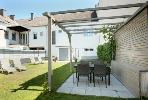 a patio with a table and chairs under a pergola at CAMPANELL - Das Ferienhaus im Blaufränkischland in Deutschkreutz