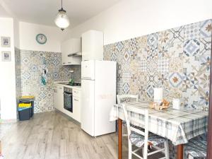 a kitchen with a white refrigerator and a table at Affittacamere DOMO AGORA' in Tertenìa