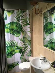 a bathroom with a sink and a leaf shower curtain at La Naranxa in Bárzana