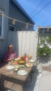 Una mujer sentada en una mesa con comida. en Sørlandsidyll nær by og Dyreparken en Grimstad