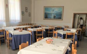a dining room with white tables and chairs and a man standing in the doorway at Hotel Holiday in Giulianova