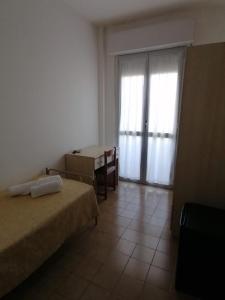 a bedroom with two beds and a desk and a window at Hotel Holiday in Giulianova