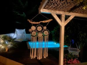 un groupe d'horloges de rêve suspendues à une pergola la nuit dans l'établissement Villa Zen avec 2 chats, à Grospierres