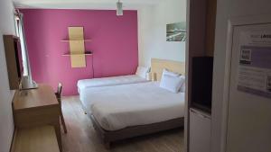 サン・プリエストにあるEastLodge Lyon Est Eurexpoのピンクの壁の小さなベッドルーム(ベッド1台付)