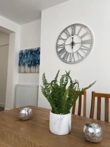 une plante dans un vase blanc sur une table avec une horloge dans l'établissement Stay - The Wellington Burton on Trent, à Burton-on-Trent