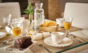 a table with a plate of cake and cups of coffee at Albergo Diffuso Birkin Castello in Cagliari