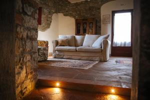 a living room with a couch and a stone wall at Podere Terreno alla via della volpaia in Radda in Chianti