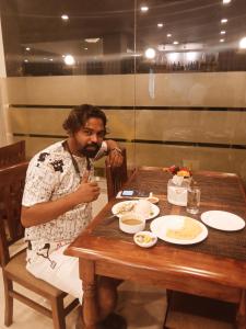 Ein Mann, der am Tisch sitzt und Essen isst. in der Unterkunft Hotel Krishna Kathmandu in Kathmandu