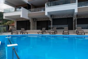 a large swimming pool with chairs and a building at Katerina Luxurious Sea View in Nikiana