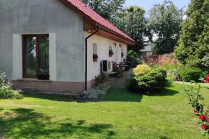 une petite maison avec une cour avec de l'herbe dans l'établissement Rooms in Rodowe Siedlisko Lechja, 