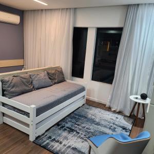 um quarto com uma cama, uma cadeira e uma janela em Eco Flat Recife - Vista ao Mar de Boa Viagem no Recife