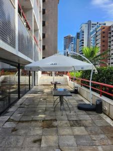 uma mesa com um guarda-chuva branco em frente a um edifício em Eco Flat Recife - Vista ao Mar de Boa Viagem no Recife