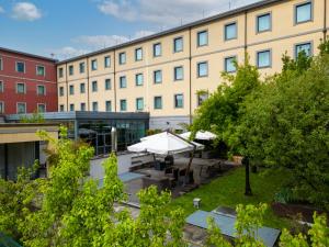 budynek ze stołem i parasolem przed nim w obiekcie Best Western Falck Village Milano Sesto w mieście Sesto San Giovanni