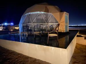 a tent with chairs and tables in the water at night at Rum Armony camp in Wadi Rum