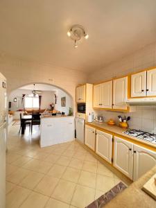 a large kitchen with white cabinets and a dining room at Villa Elena in Midoun