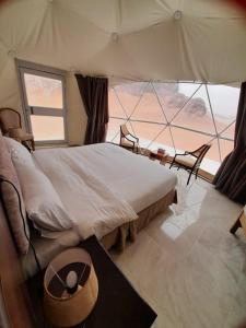 a bedroom with a large bed and a large window at Rum Armony camp in Wadi Rum