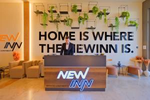 NewInn Hotel Apartments - Cadde 54 Mall في ساكاريا: رجل يقف على منصة في غرفة بها لافتة