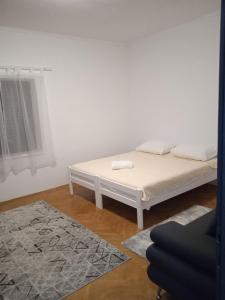 Cama blanca en habitación con alfombra en D&D Lausic Apartment, en Dugi Rat