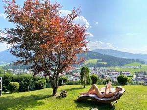 two women laying on a chair in a field with a tree at Appartement Thunhart Wilfried&Elisabeth in Altenmarkt im Pongau