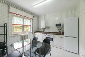 a kitchen with a glass table and a refrigerator at Villa Vacacional Toró Playa in Llanes