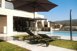 a pair of chairs and an umbrella next to a pool at Chalet de diseño moderno en Sanxenxo in Sanxenxo