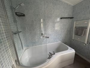 uma casa de banho com uma banheira e um chuveiro em vidro. em Woodpecker Lodge em Newquay