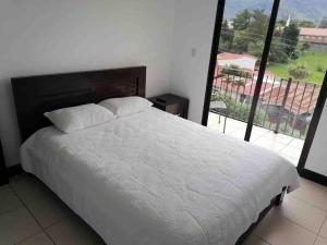 1 dormitorio con cama blanca y ventana grande en Namaje Tres Ros en Tres Ríos