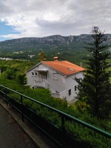 ein weißes Haus mit rotem Dach mit Bergen im Hintergrund in der Unterkunft Apartment Sana in Bribir