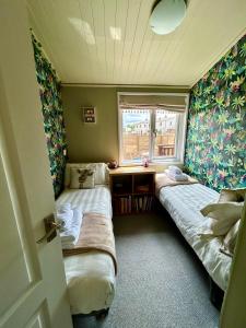 Duas camas num pequeno quarto com uma janela em Woodpecker Lodge em Newquay